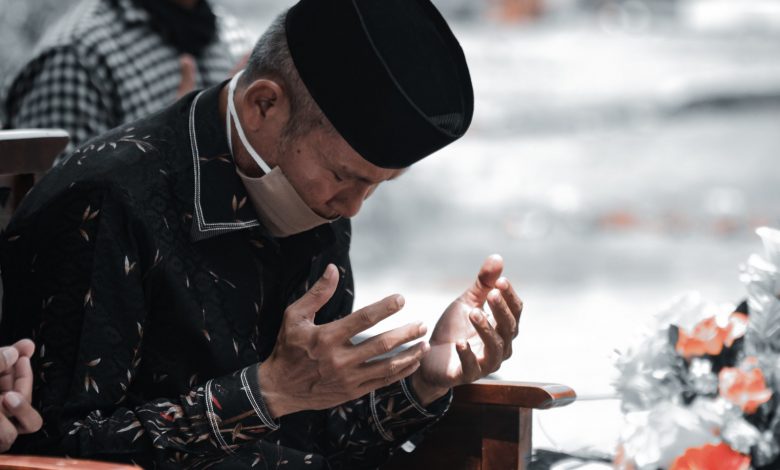 Man in Black Leather Jacket and Black Knit Cap Sitting on Brown Wooden Chair