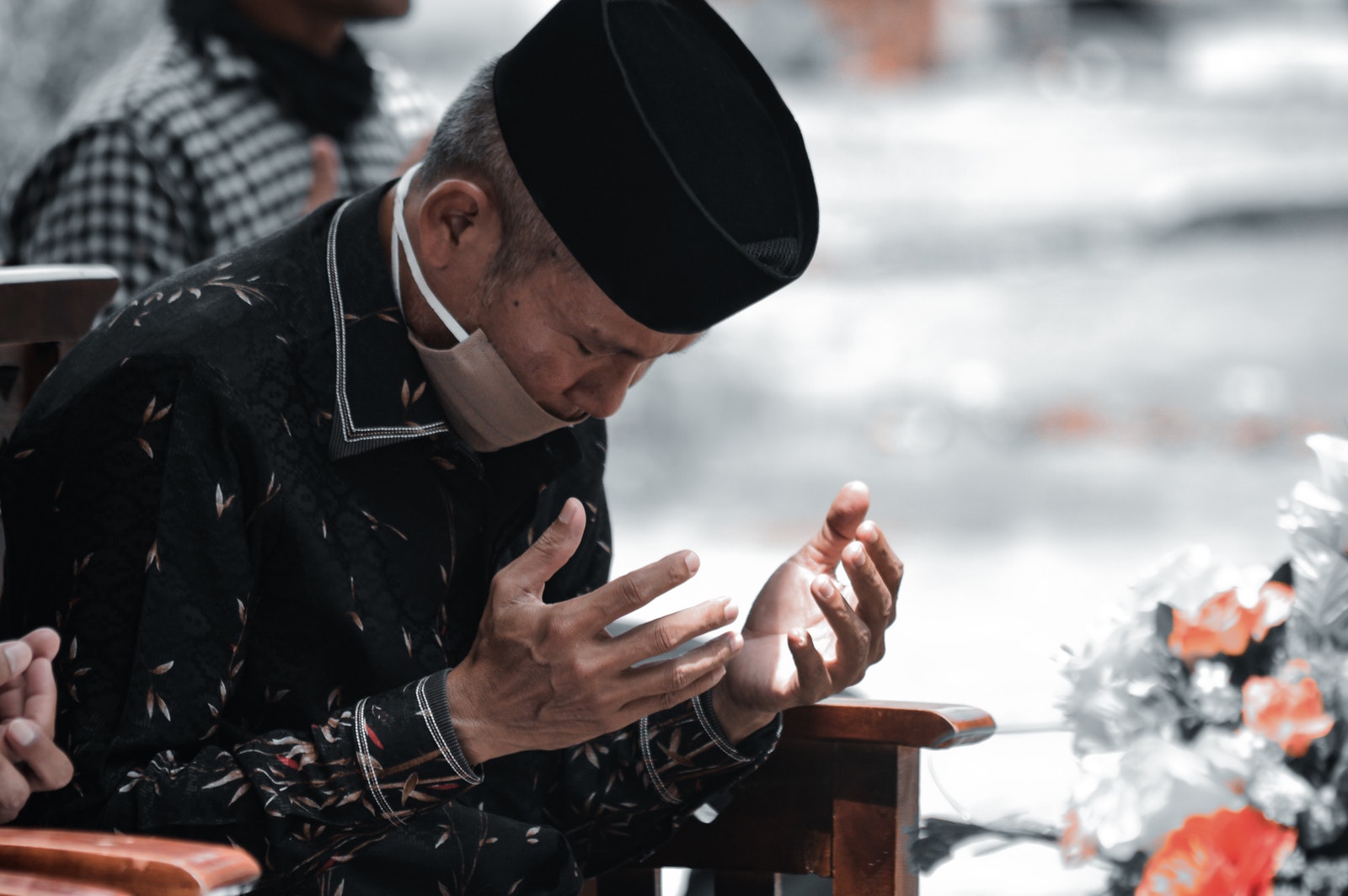 Man in Black Leather Jacket and Black Knit Cap Sitting on Brown Wooden Chair